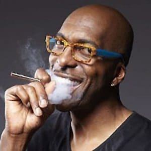 Ex-Detroit Piston's player, John Salley smoking a cigar and smiling.