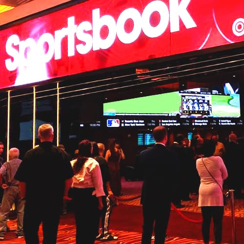 Sportsbook sign with people standing under it.